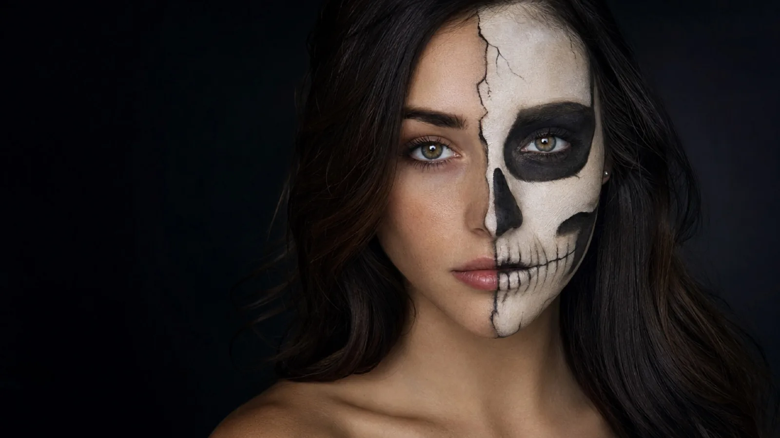 Fictional adult with split-face half-skull Halloween makeup, one human side and one painted bone side